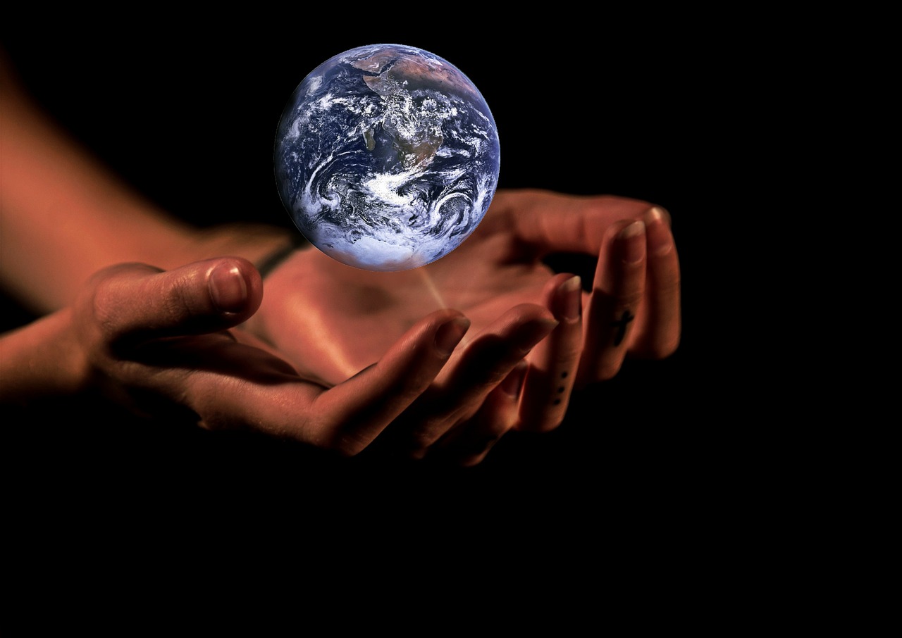 An image of earth resting above two hands which are cupped around it.